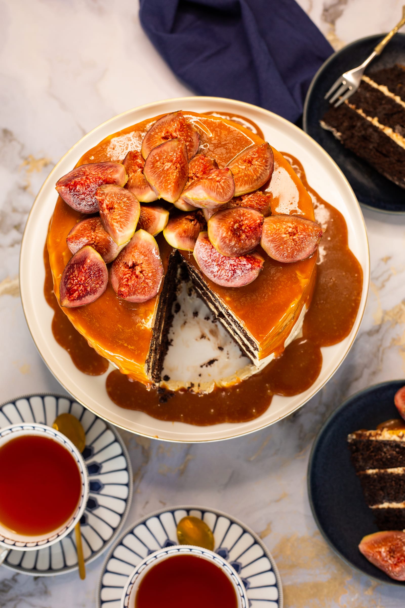 The cut devil's food cake with slices and cups of tea around it, from above
