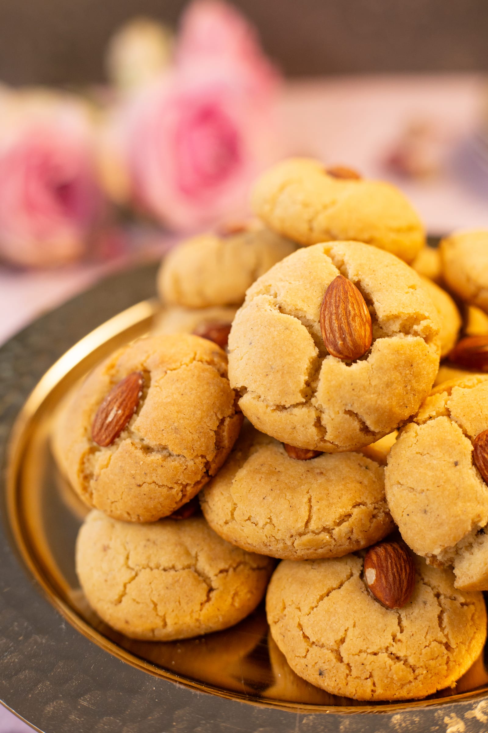 Close-up of crackled naan kathai, each topped with an almond