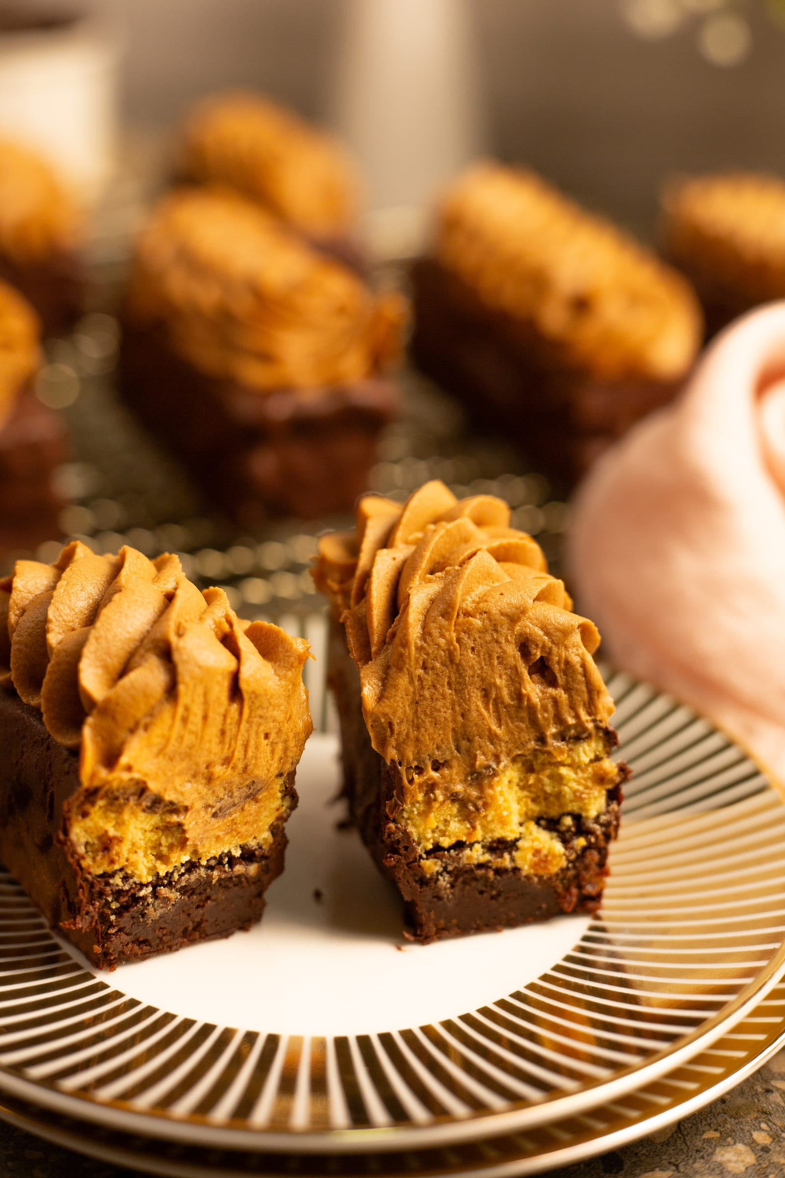 Two channa magaj and chocolate brownie fingers cut open on a gold-striped plate, showing the brownie and channa magaj layers