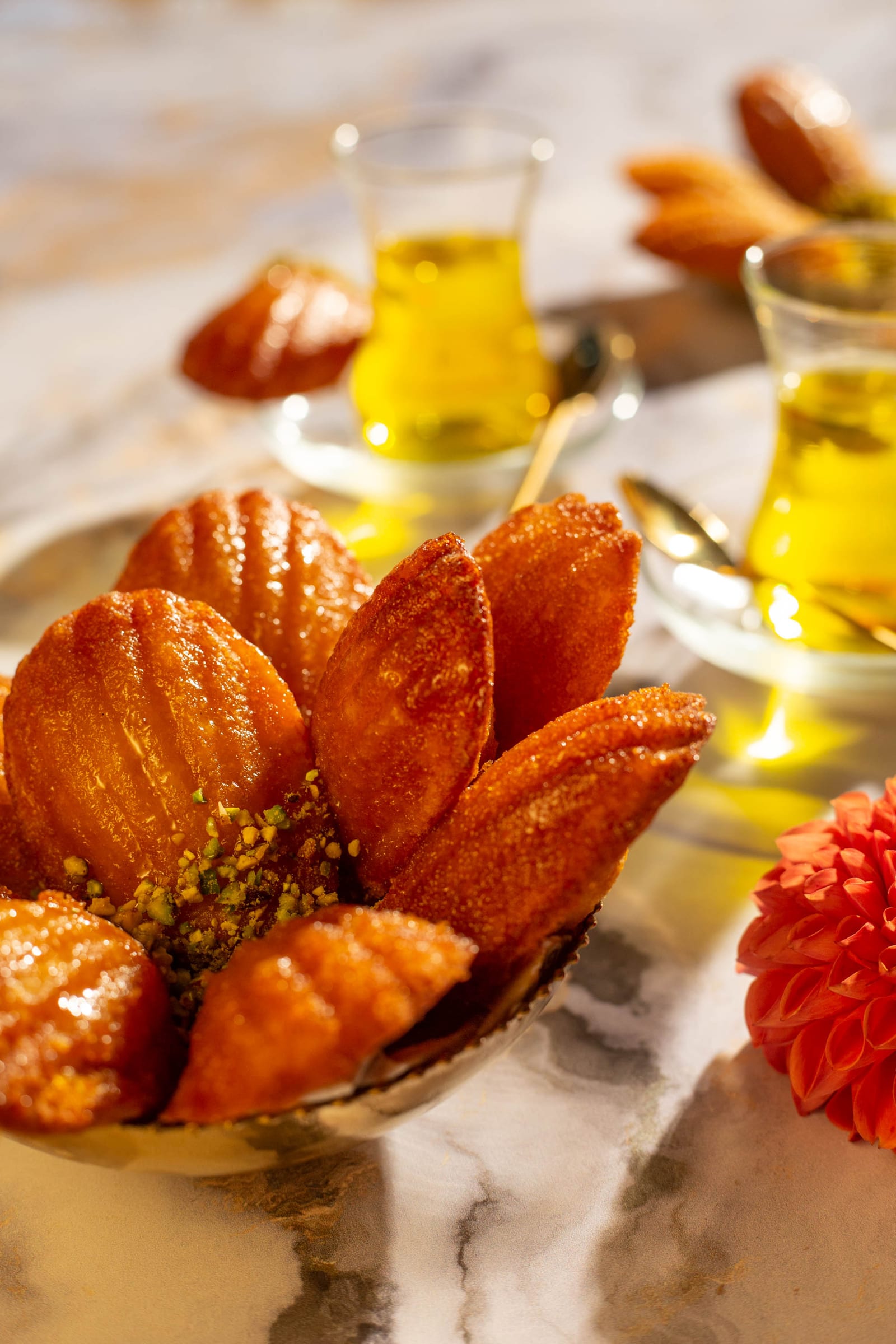 Orange and honey madeleines arranged in a gold bowl