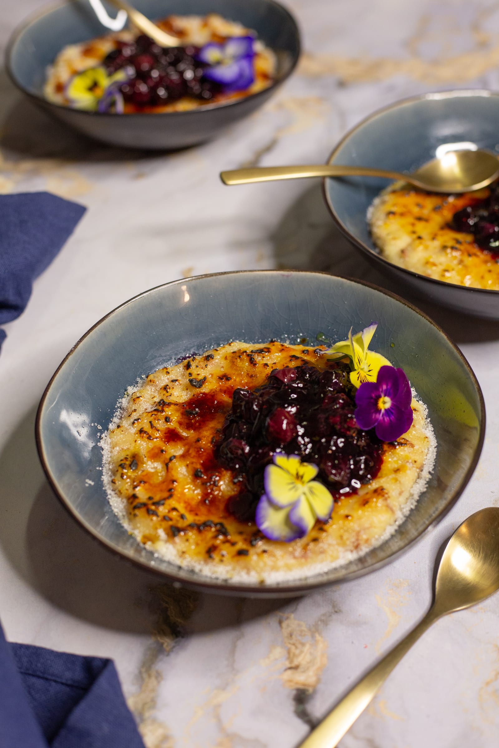 Bowls of kheer brûlée beside a navy napkin