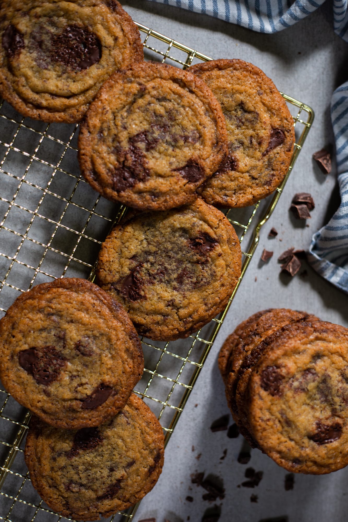 Pan banging chocolate chip cookies on a gold rack with chocolate chunks, from above