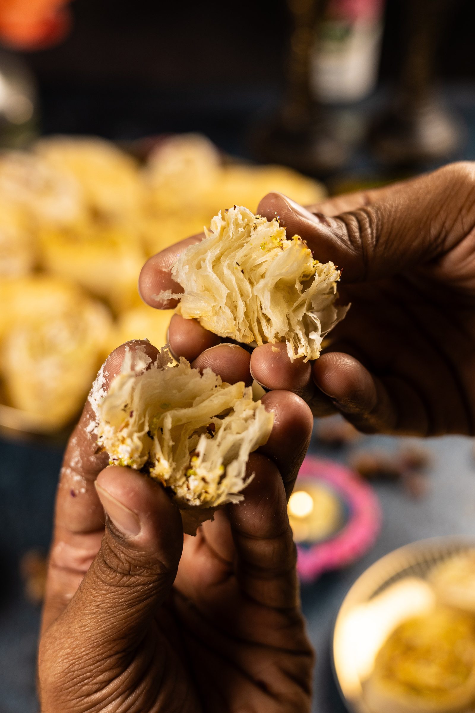 Hands pulling apart a banana puri to show its flaky layers