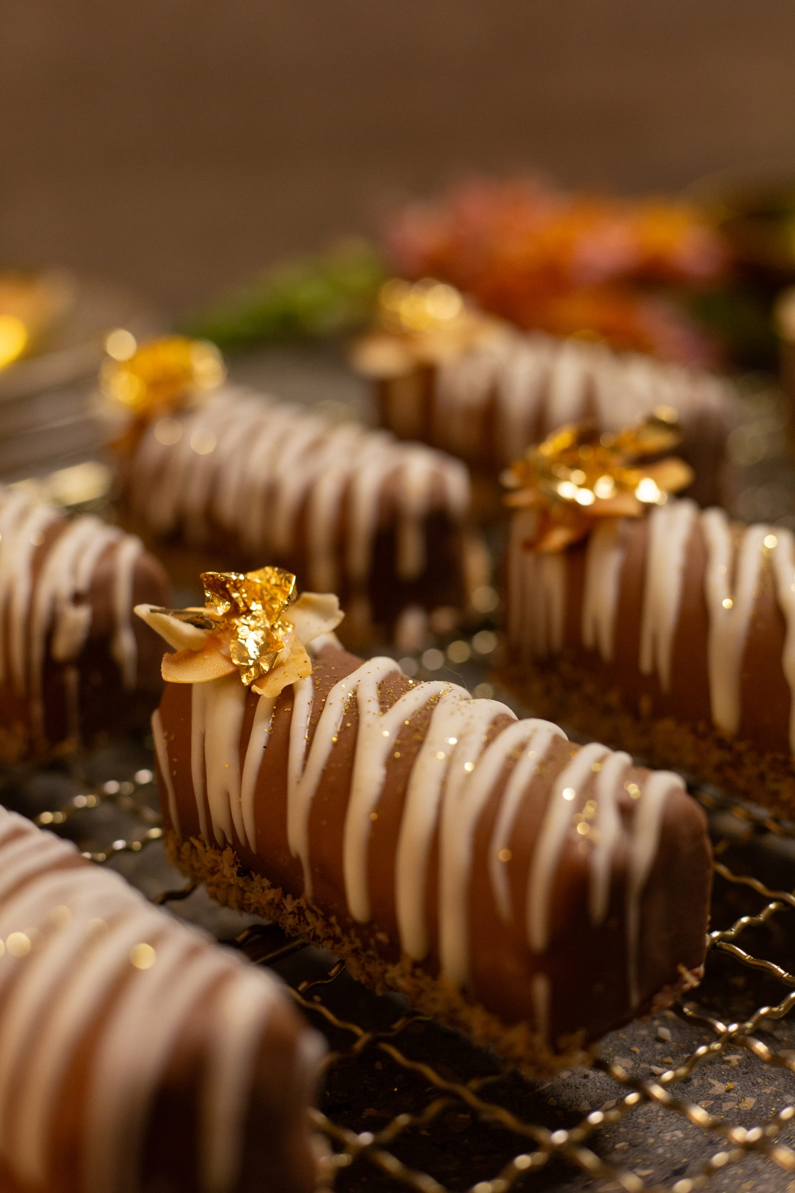 Coconut, caramel and chocolate logs lined up on the rack with orange flowers behind