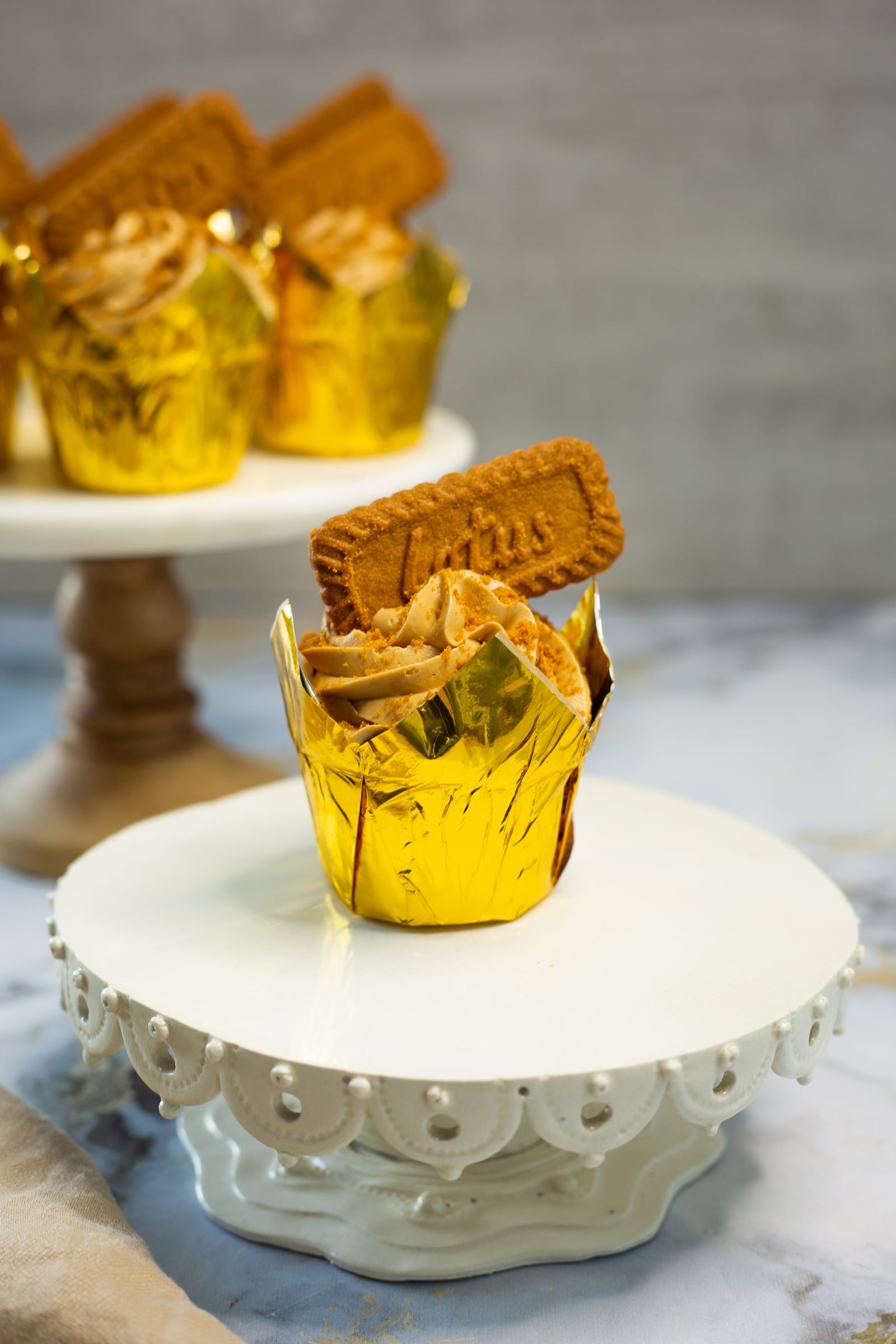 A single Biscoff cupcake on a white cake stand