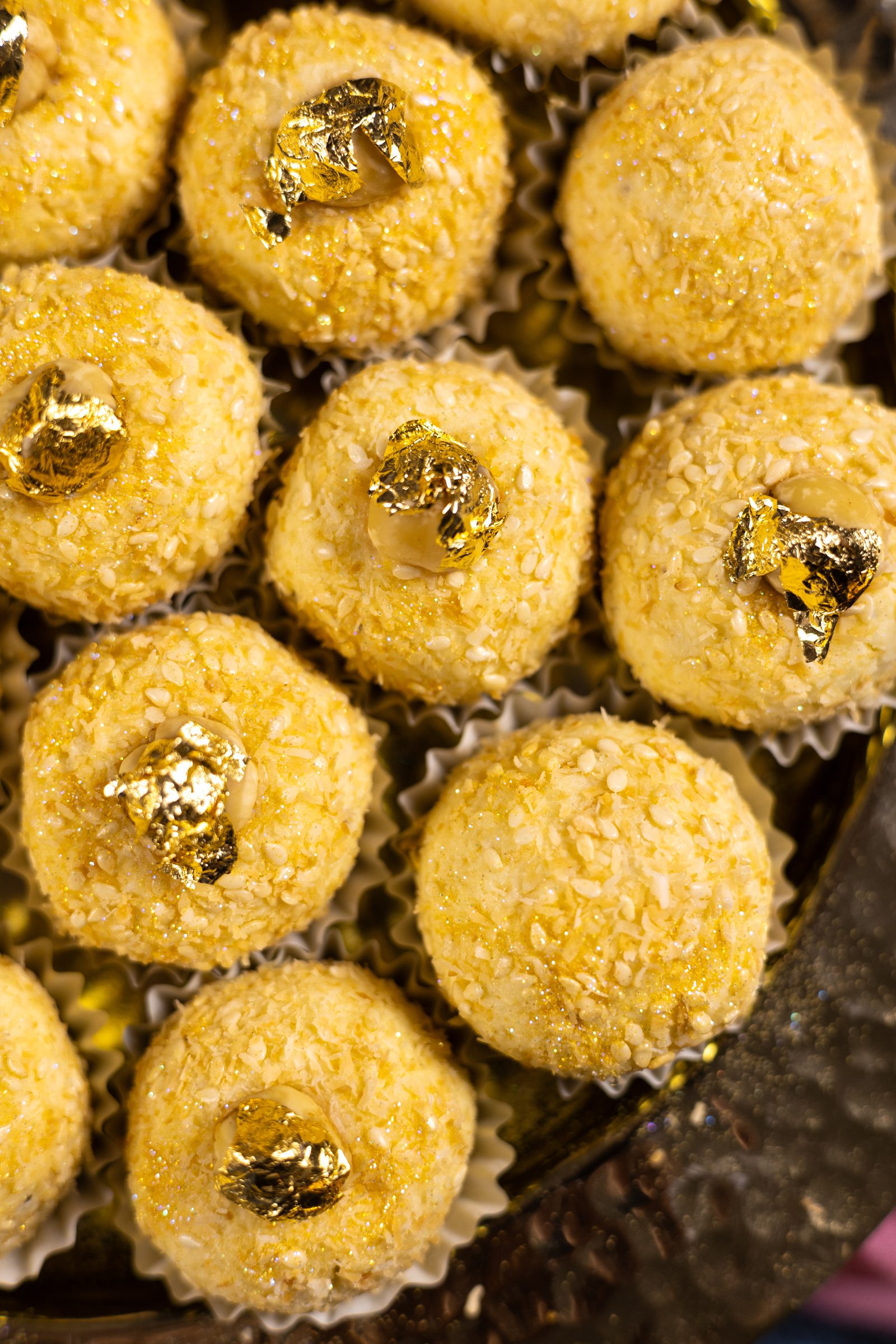 Close-up of coconut Simply Wonderfuls from above, showing the toasted coconut and sesame coating and gold leaf