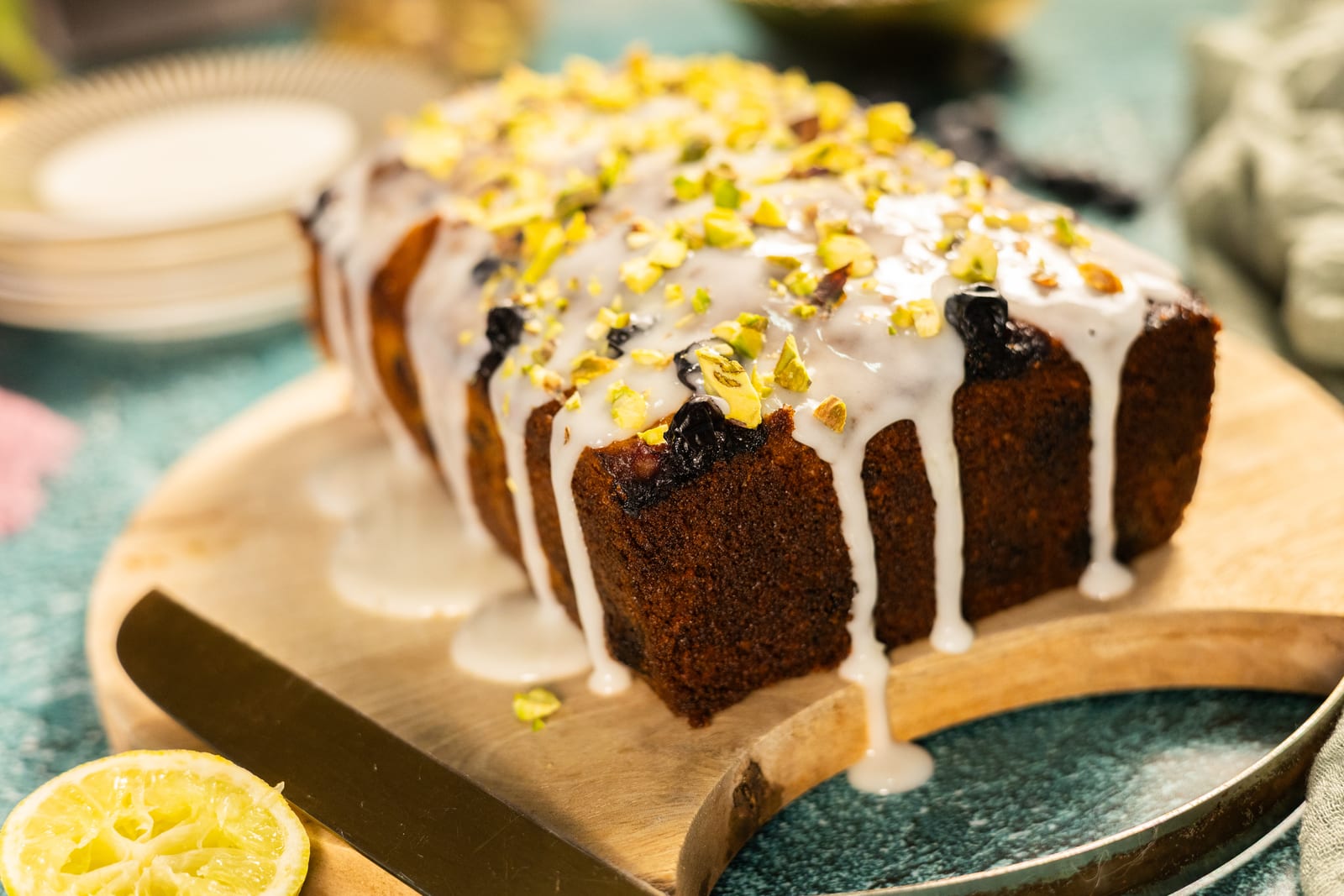 Close-up of lime glaze dripping down the loaf, scattered with pistachios