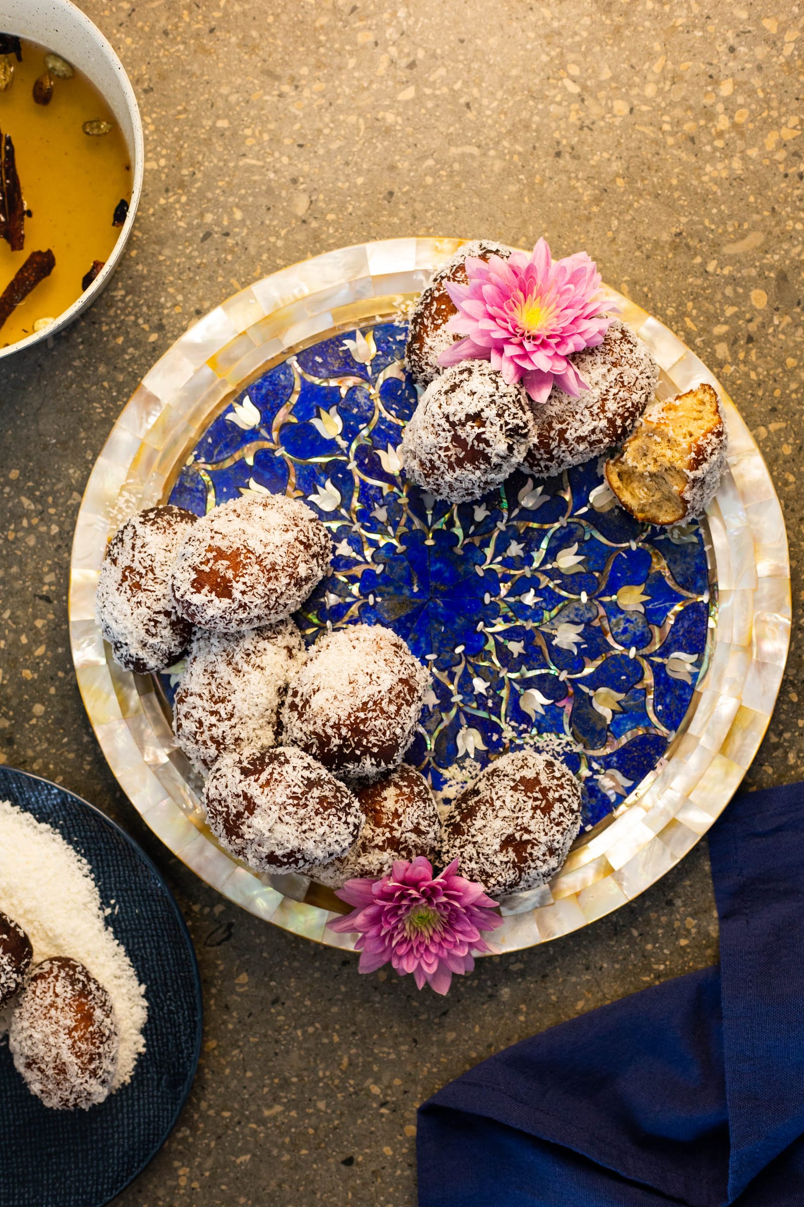Cape Malay koesisters on a blue mosaic plate next to a bowl of syrup, from above